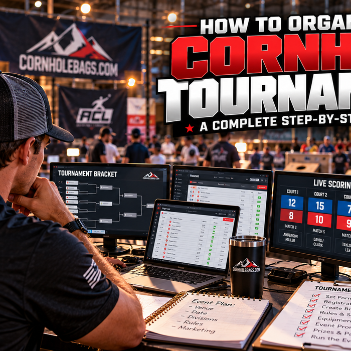 Cornhole tournament director managing player registrations, tournament brackets, and live scoring on multiple monitors at a competitive cornhole event.